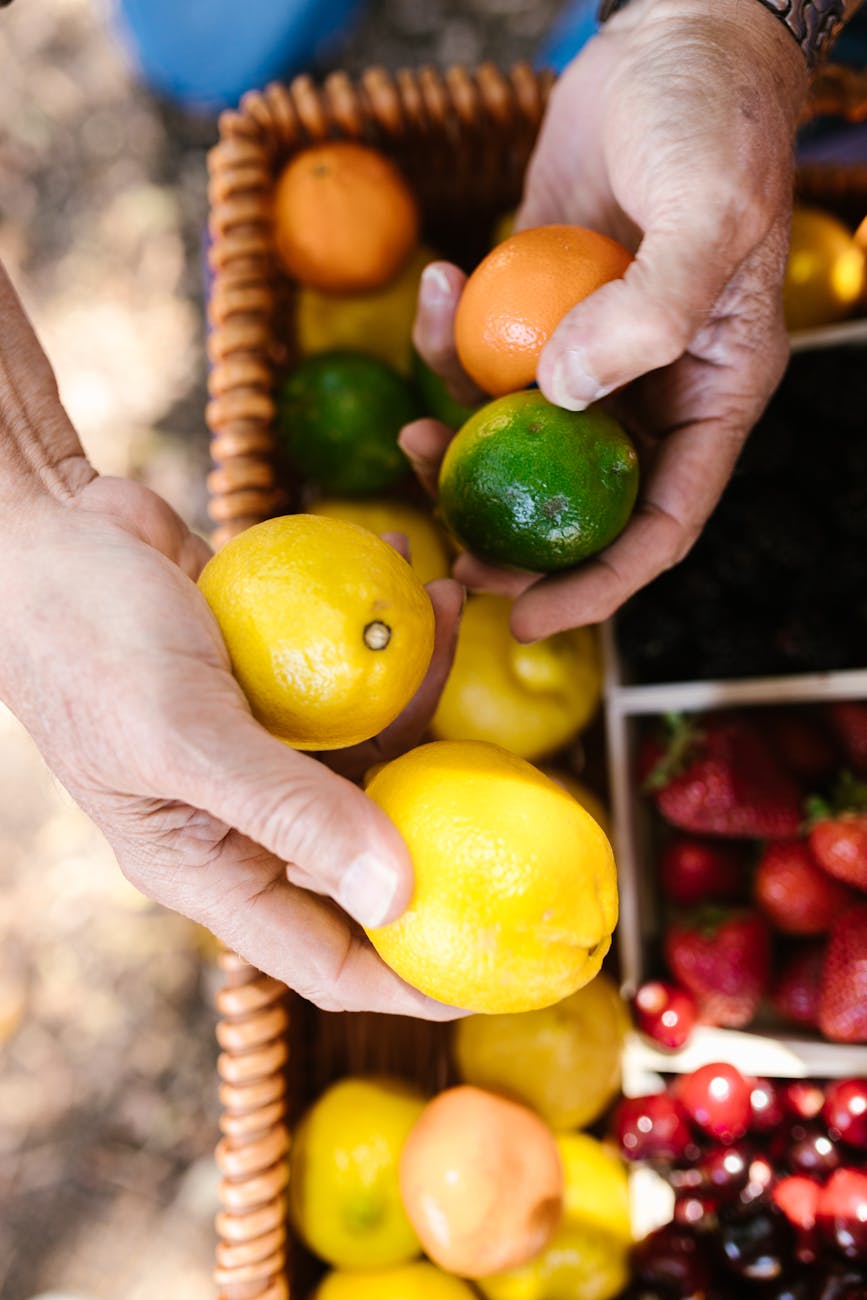 hands of a person holding lemons and lime